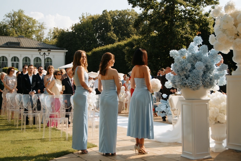 Ceremonia w ogrodzie Pałacu Mała Wieś - trzy druhny w błękitnych sukniach, za nimi goście